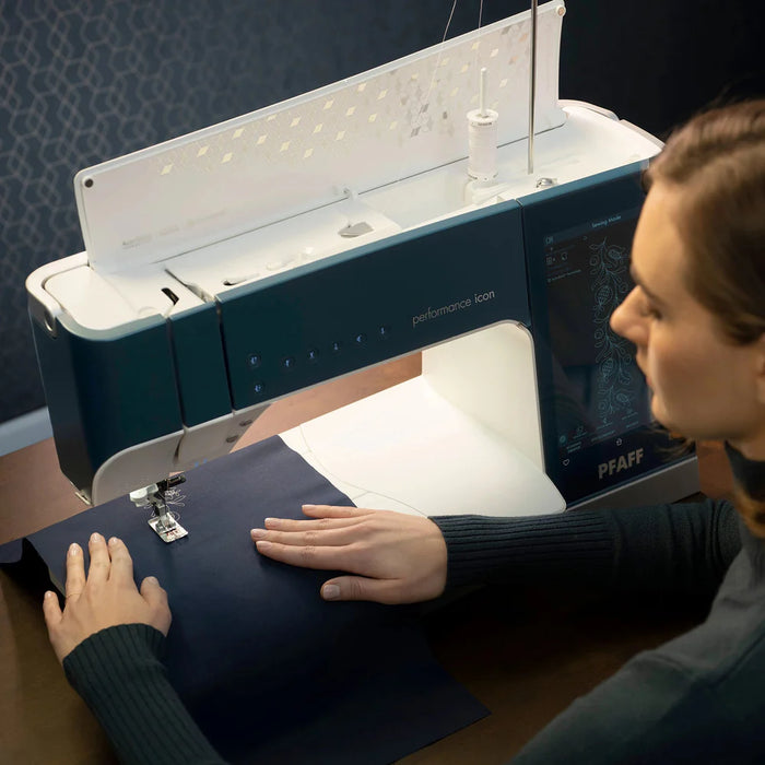 Person using a PFAFF sewing machine with a dark background