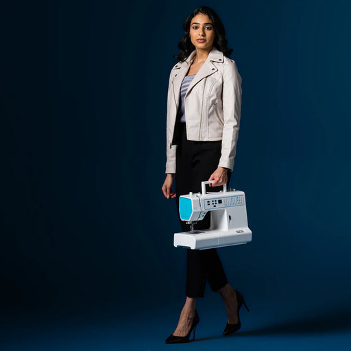 Woman holding a portable sewing machine against a dark blue background