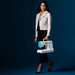 Woman holding a portable sewing machine against a dark blue background