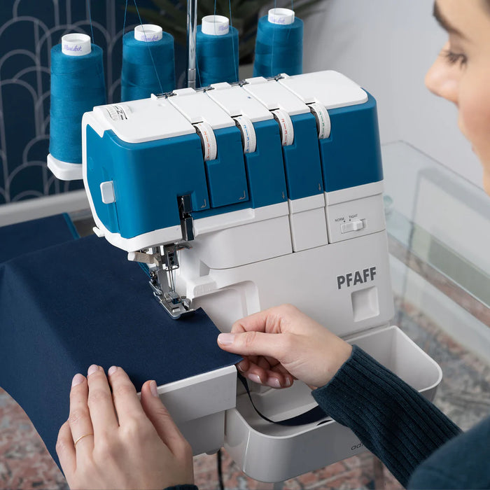 PFAFF sewing machine with blue thread and a person operating it.