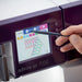 Person using a stylus to interact with the touchscreen of a embroidery machine labeled 'admire air 7000'.