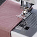 Sewing machine needle stitching pink fabric