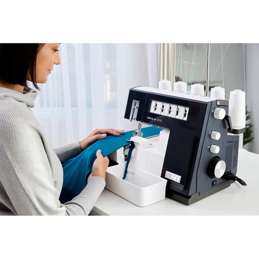 Woman using a sewing machine on a white table with a blurred background
