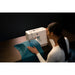 Person using a sewing machine on a dark background