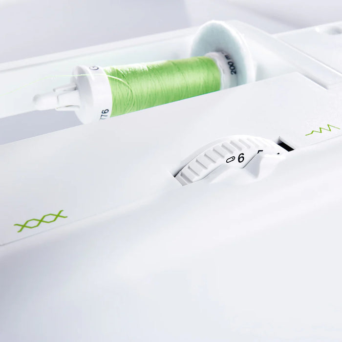 Close-up of a white sewing machine with green thread and needle