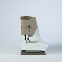 Coffee machine with beige top and white body on a light gray background