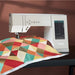 Sewing machine with a colorful geometric quilt on a brown background