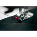 Close-up of a sewing machine needle stitching fabric