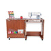 Arrow Judy 105 Sewing Cabinet in Teak with sewing machine installed, extended workspace, and front storage cubby filled with colorful thread and fabric.