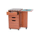 Teak Kangaroo Kiwi Storage Cabinet K7105 with thread drawer open, ironing board on top, and side table extended for sewing tasks.