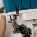 Close-up of a person adjusting a blue and white sewing machine.