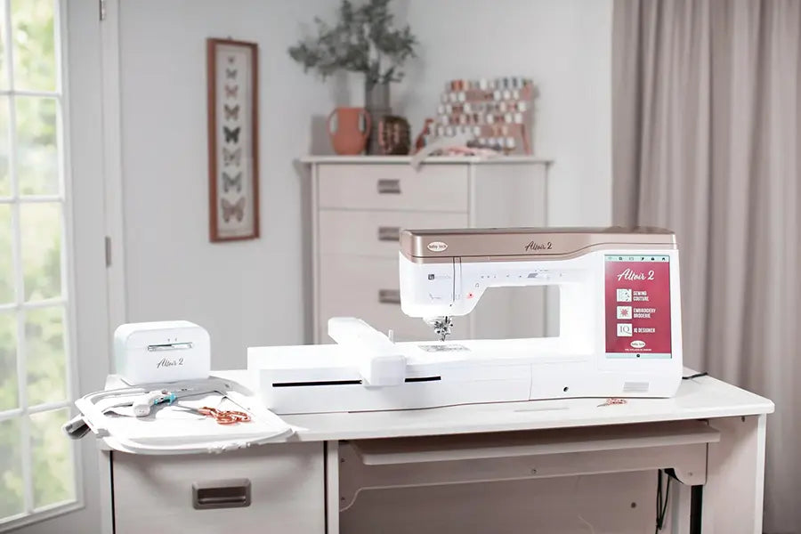 Baby Lock Altair 2 sewing and embroidery machine set up in a craft room with embroidery hoops, tools, and storage drawers.