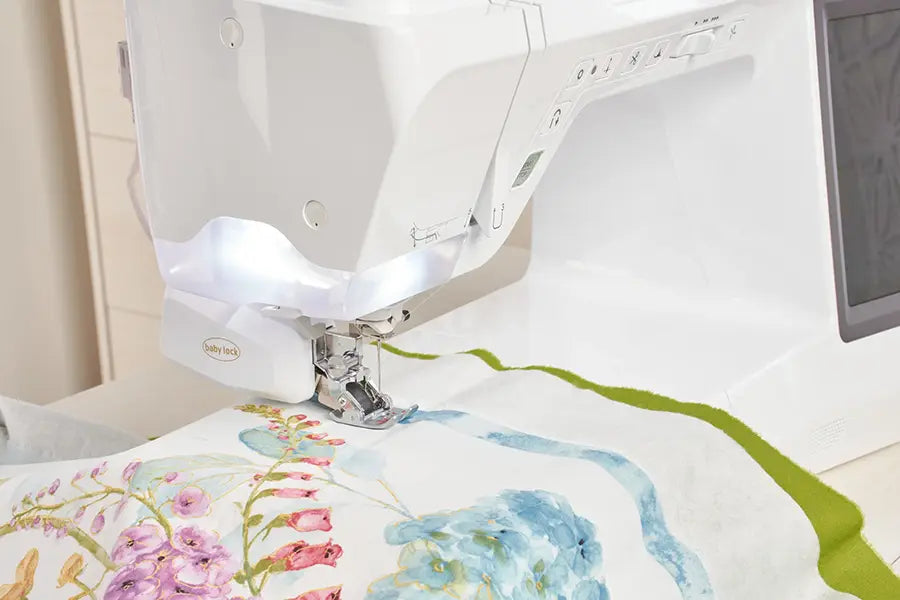 Close-up of Baby Lock BLBA Ballad quilting machine stitching colorful fabric with bright LED lighting.