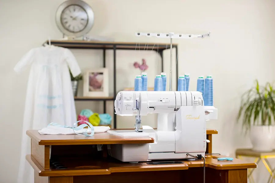 Baby Lock Triumph 50th Anniversary Edition serger set up in a sewing studio, demonstrating workspace integration and multi-thread functionality.