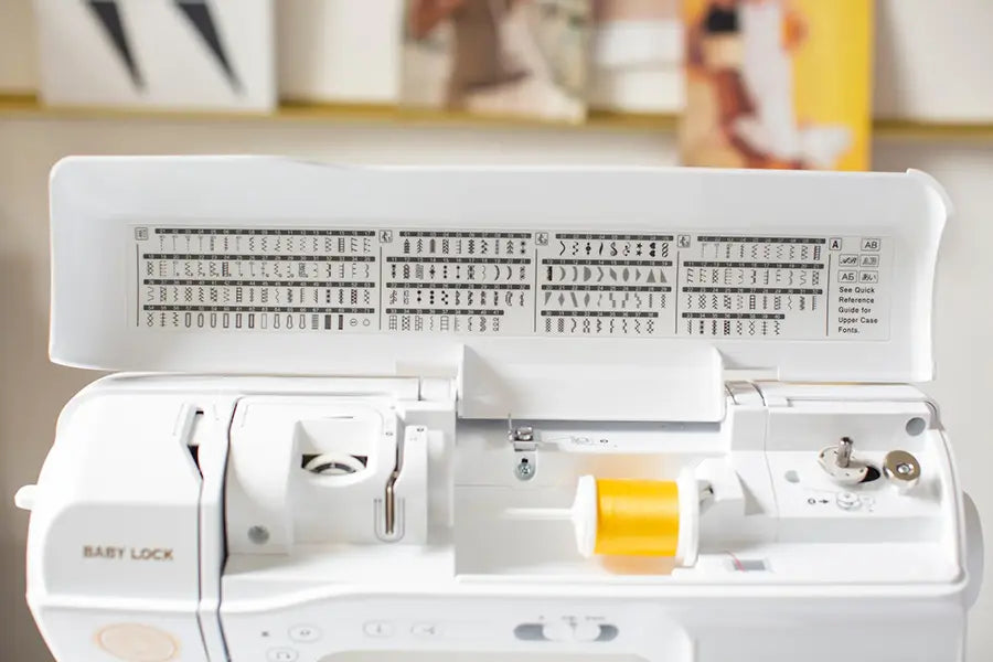 Baby Lock Brilliant sewing machine upper lid open showing built-in stitch library and threading path