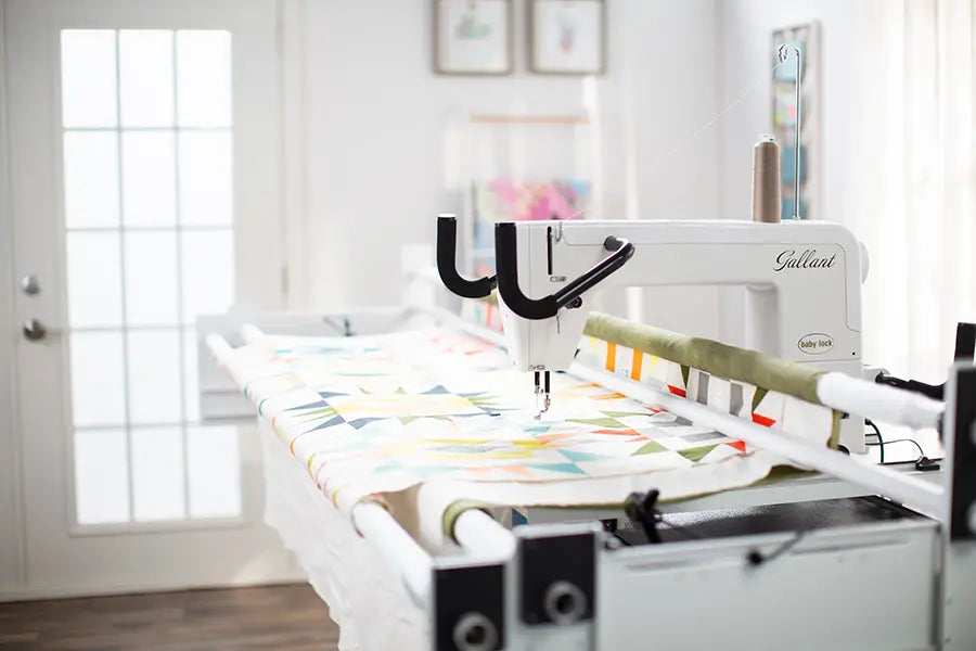 Baby Lock Gallant BLGT15 quilting machine stitching a colorful quilt on the Villa frame in bright sewing studio.