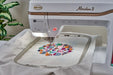 Close-up of Baby Lock Meridian 2 embroidery machine stitching a vibrant multicolor design inside the 9.5 x 14 hoop, highlighting precision Needle Beam placement.