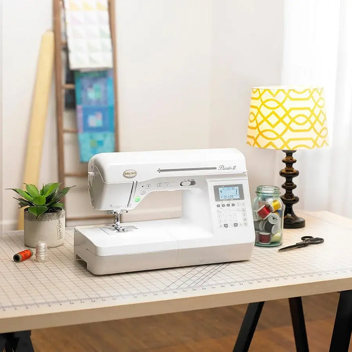Baby Lock Presto II sewing machine displayed on worktable with sewing notions and quilting décor