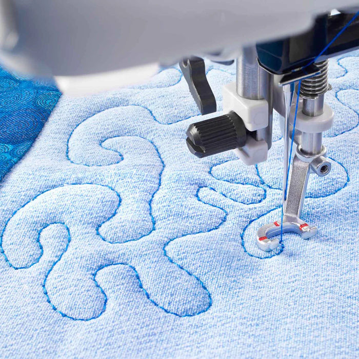 Sewing machine needle stitching on a piece of blue fabric