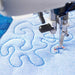 Sewing machine needle stitching on a piece of blue fabric