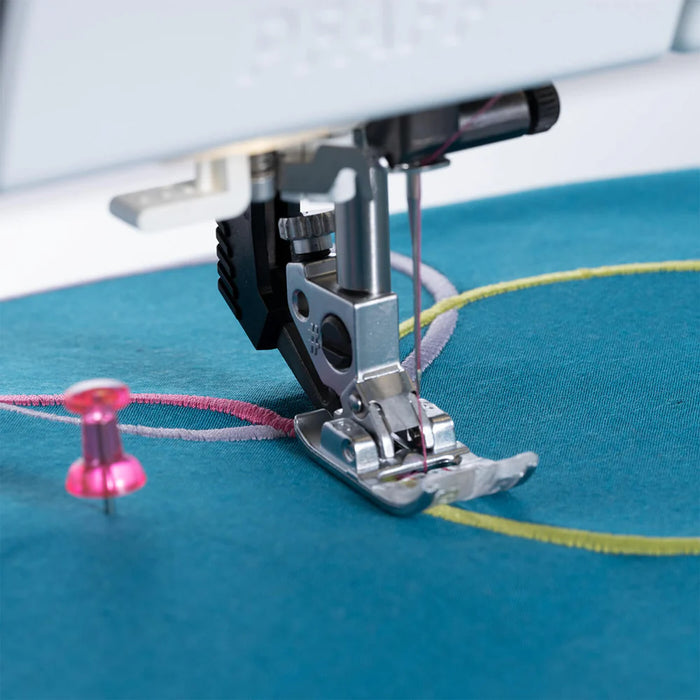Sewing machine needle on blue fabric with pink thread