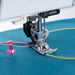 Sewing machine needle on blue fabric with pink thread