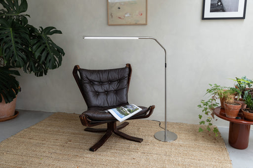Brushed steel Daylight Slimline 4 LED floor lamp illuminating a reading chair, showcasing sleek modern design and high-CRI task lighting for home and studio use.