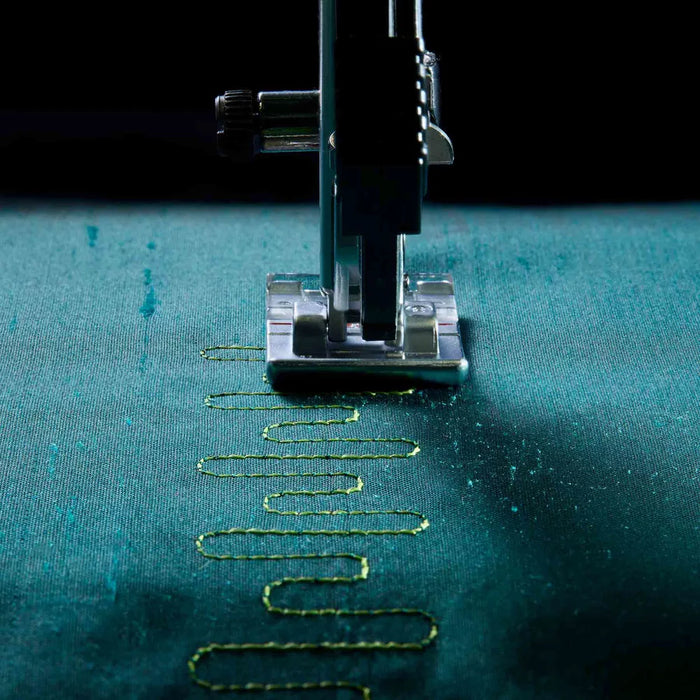Sewing machine needle stitching on teal fabric