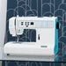 White and blue sewing machine on a glass surface with a patterned blue background