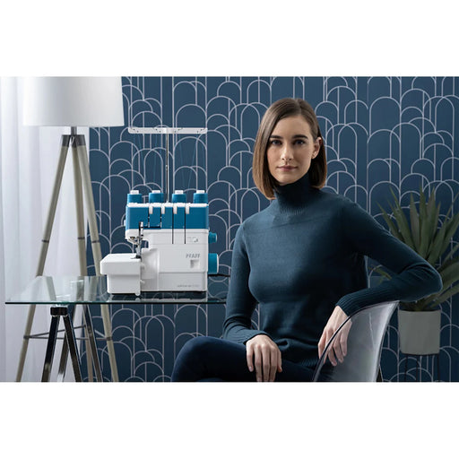 Woman sitting in a modern room with a sewing machine on a table.
