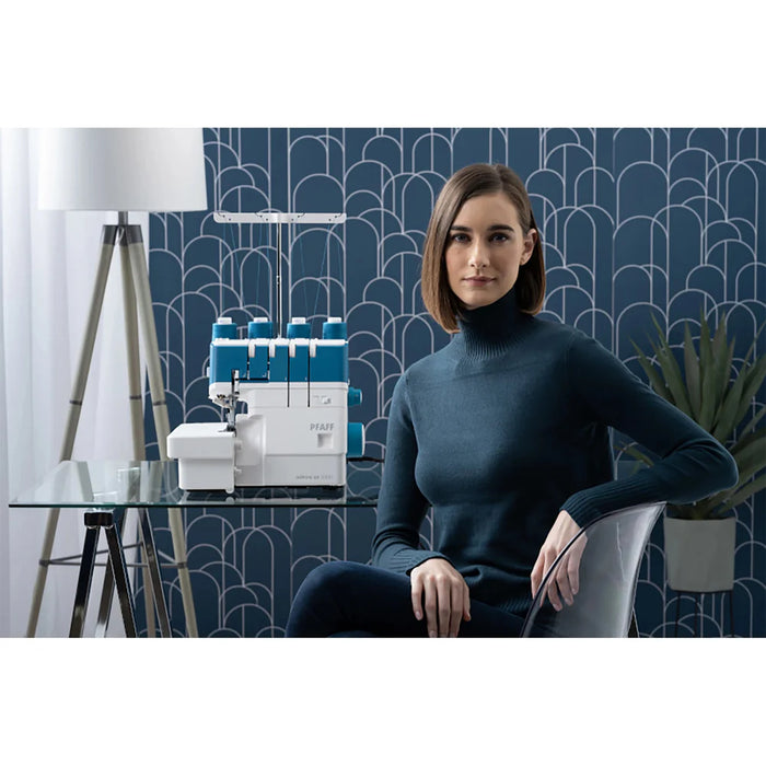 Woman sitting in a modern room with a sewing machine on a table.