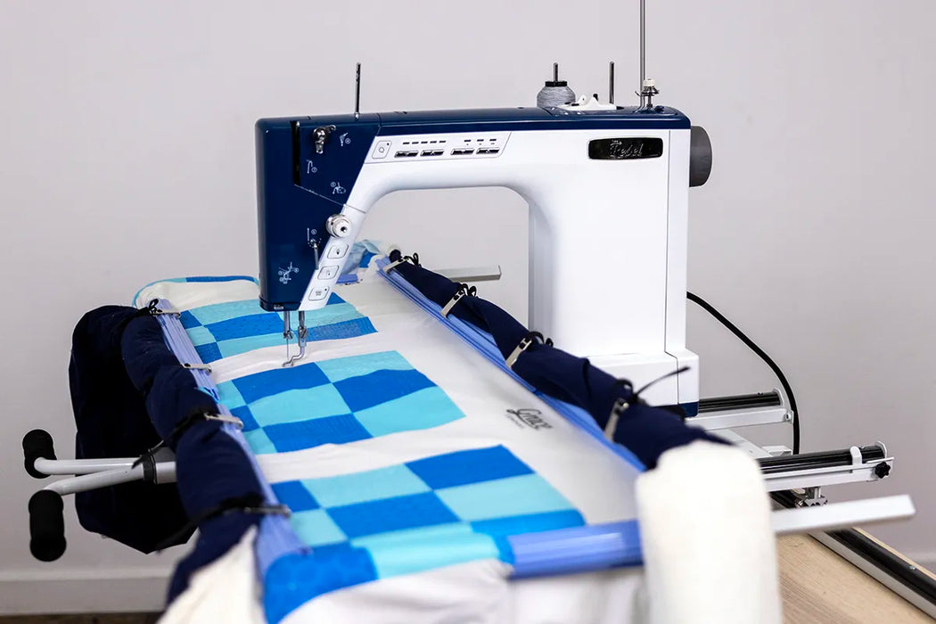 Grace Little Rebel quilting machine mounted on a quilting frame stitching a patchwork quilt with smooth stitch control