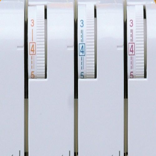 Close-up of Janome CoverPro 1000CPX tension dials for adjusting coverstitch settings on different fabrics.