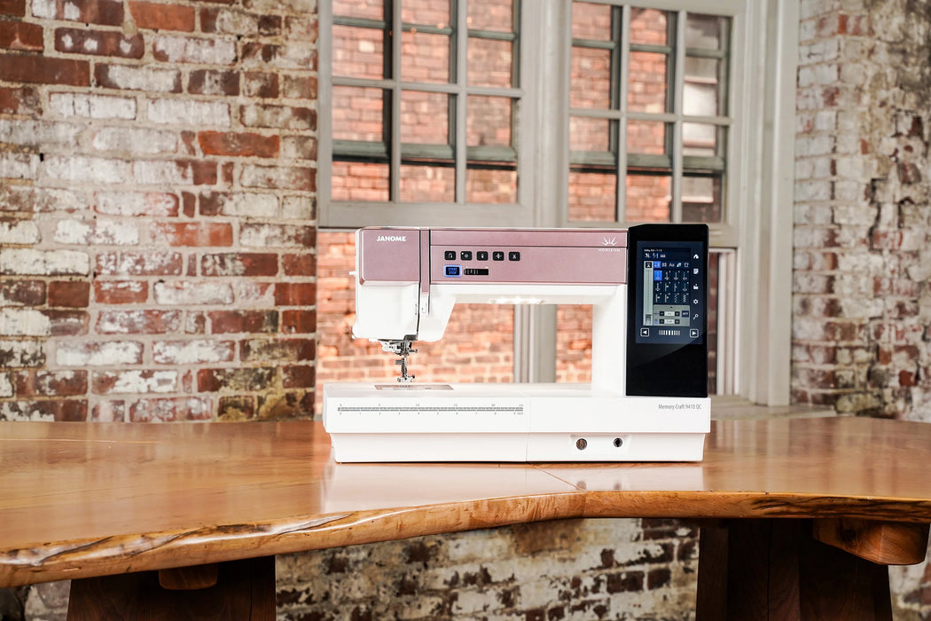 Janome Horizon Memory Craft 9410QC sewing and quilting machine displayed in a studio setting on a wooden table.