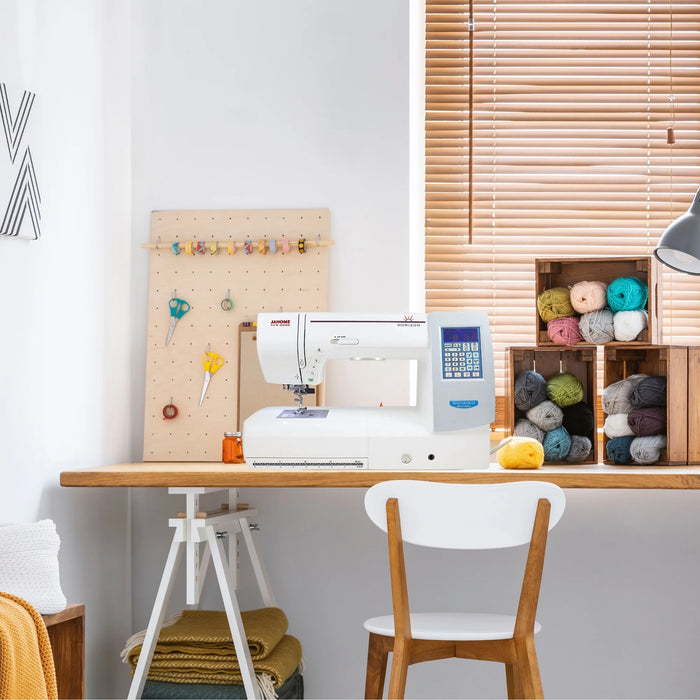 Janome Horizon Memory Craft 8200QCP SE sewing machine displayed in a modern craft room setup with yarn storage and sewing tools.