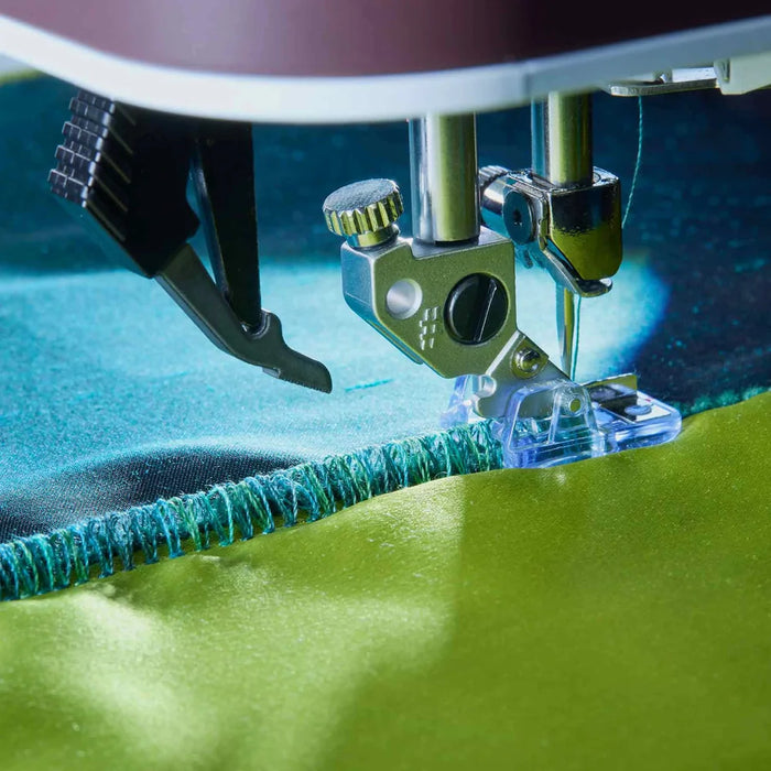 Close-up of a sewing machine needle stitching green fabric.