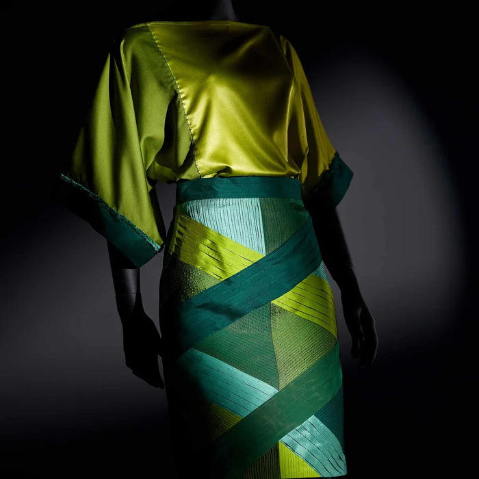 Mannequin wearing a green and blue dress with geometric pattern against a dark background