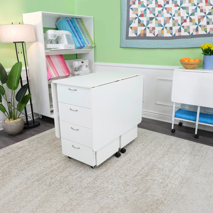Ash White Kangaroo Kookaburra Cutting Table folded into compact mode in a sewing room, showcasing drawer storage and space-saving design.