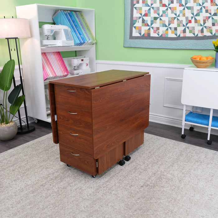 Kangaroo Kookaburra Cutting Table folded for storage inside a sewing studio, showing compact design and four front drawers.