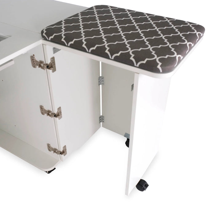 Side leaf extension with cushioned pressing mat on the Kangaroo Sydney Hydraulic XL Sewing Cabinet in white for added quilting workspace.