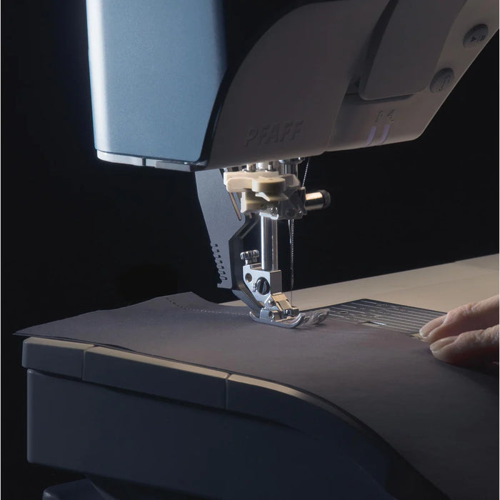 Sewing machine needle in action on a piece of fabric with a dark background