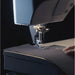 Sewing machine needle in action on a piece of fabric with a dark background