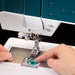 Close-up of a person using a sewing machine with a dark background