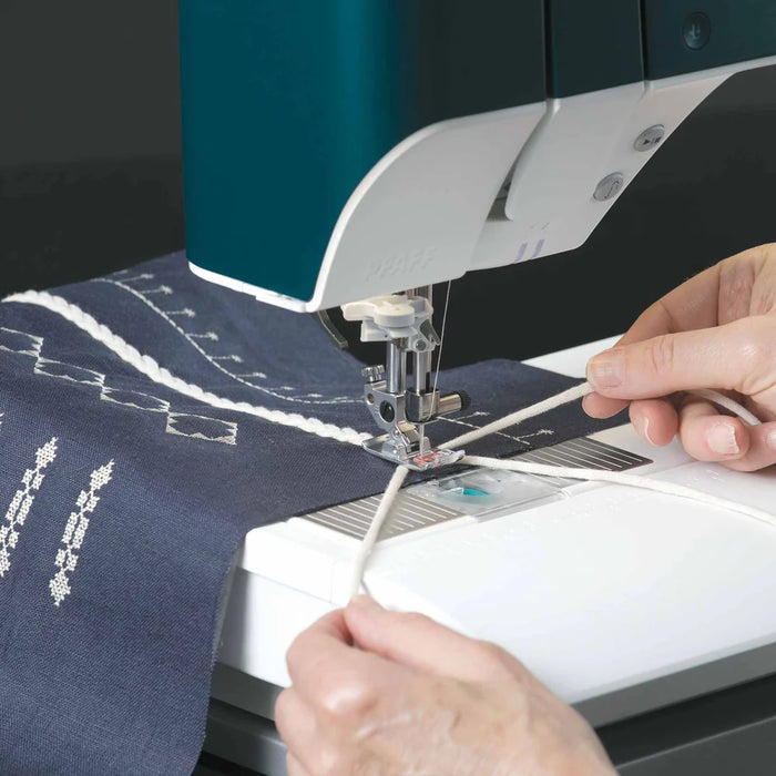 Person using a sewing machine on a piece of fabric with embroidery designs.