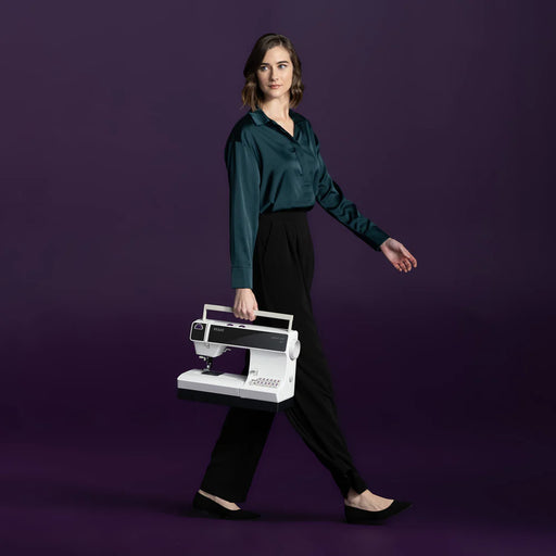 Woman holding a sewing machine against a purple background