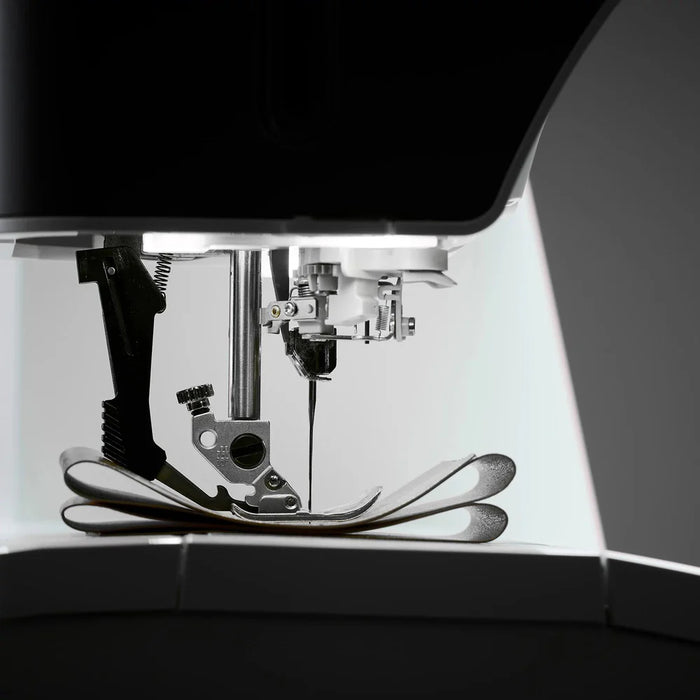 Close-up of a sewing machine needle and mechanism on a dark background