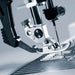 Close-up of a sewing machine needle and presser foot on a blurred background