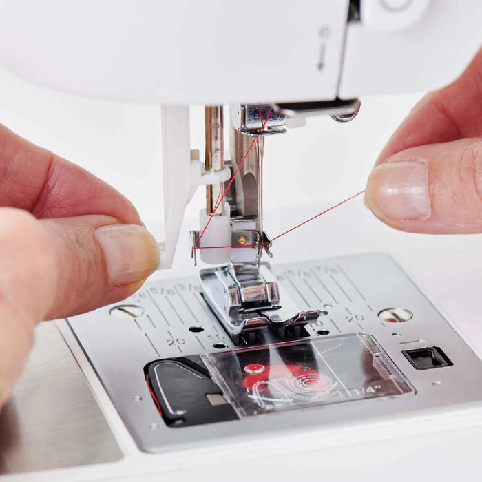Close-up of SINGER Elite CE677 sewing machine needle area demonstrating automatic needle threader and drop-in bobbin system in use
