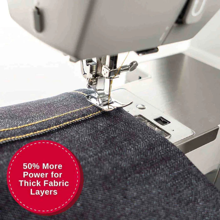 Close-up of SINGER Heavy Duty 6700C needle and presser foot sewing multiple layers of thick denim fabric