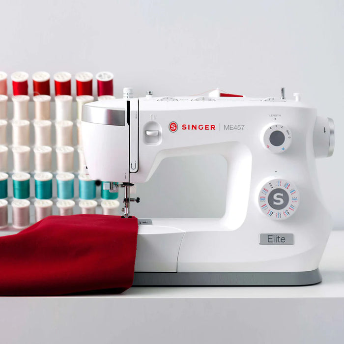 SINGER Elite ME457 sewing machine stitching red fabric with LED-lit workspace and high-speed mechanical performance